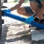A person connecting a sewer hose to the RV